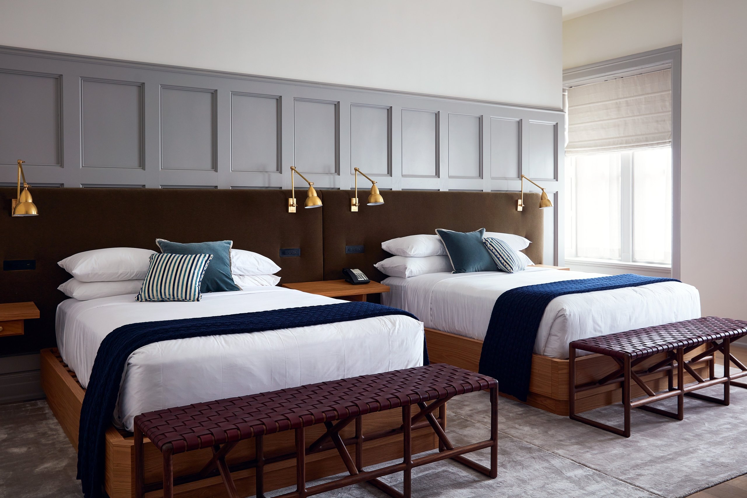 2 white queen size beds with navy blue throw blankets.