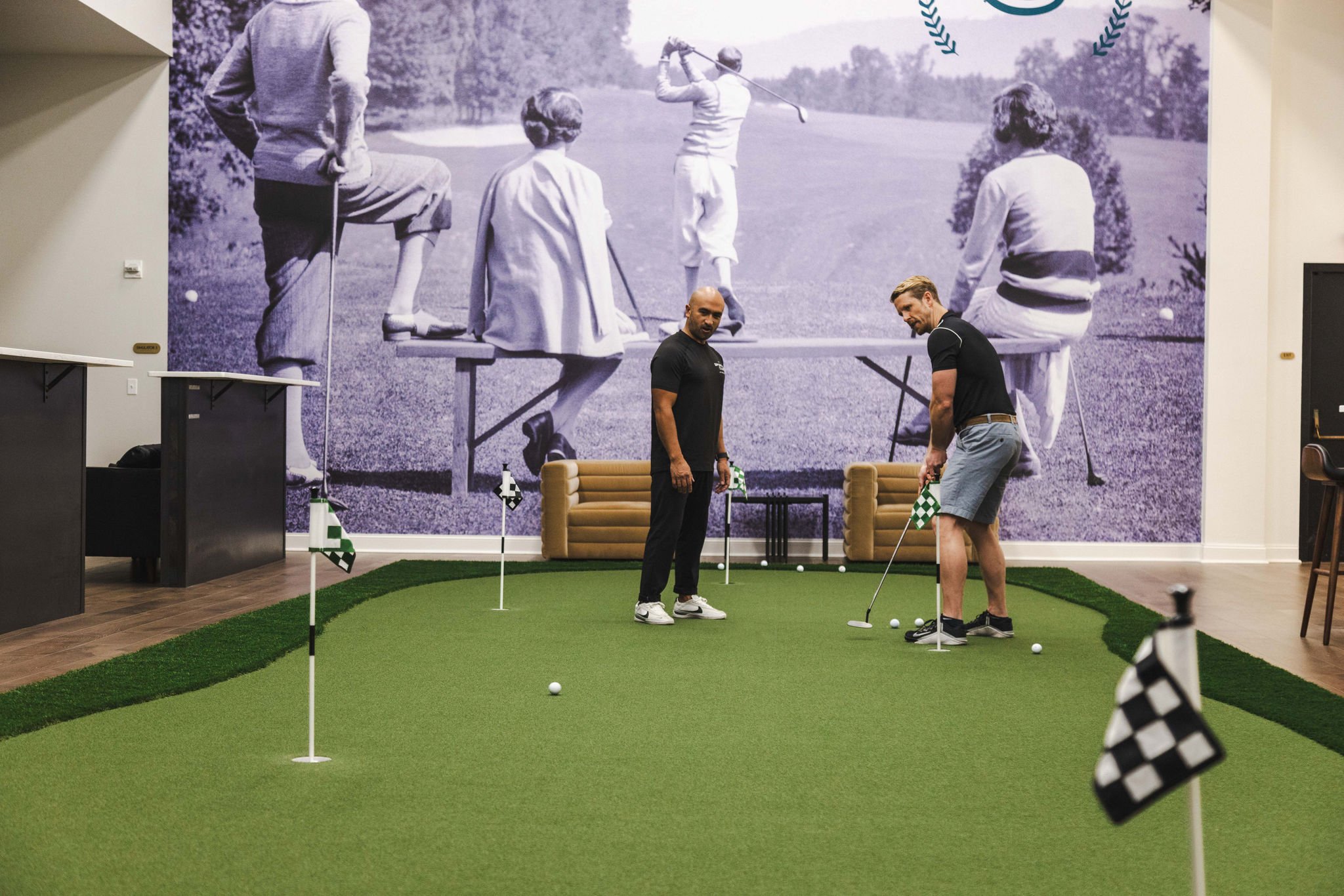 Two men are putting on an indoor green