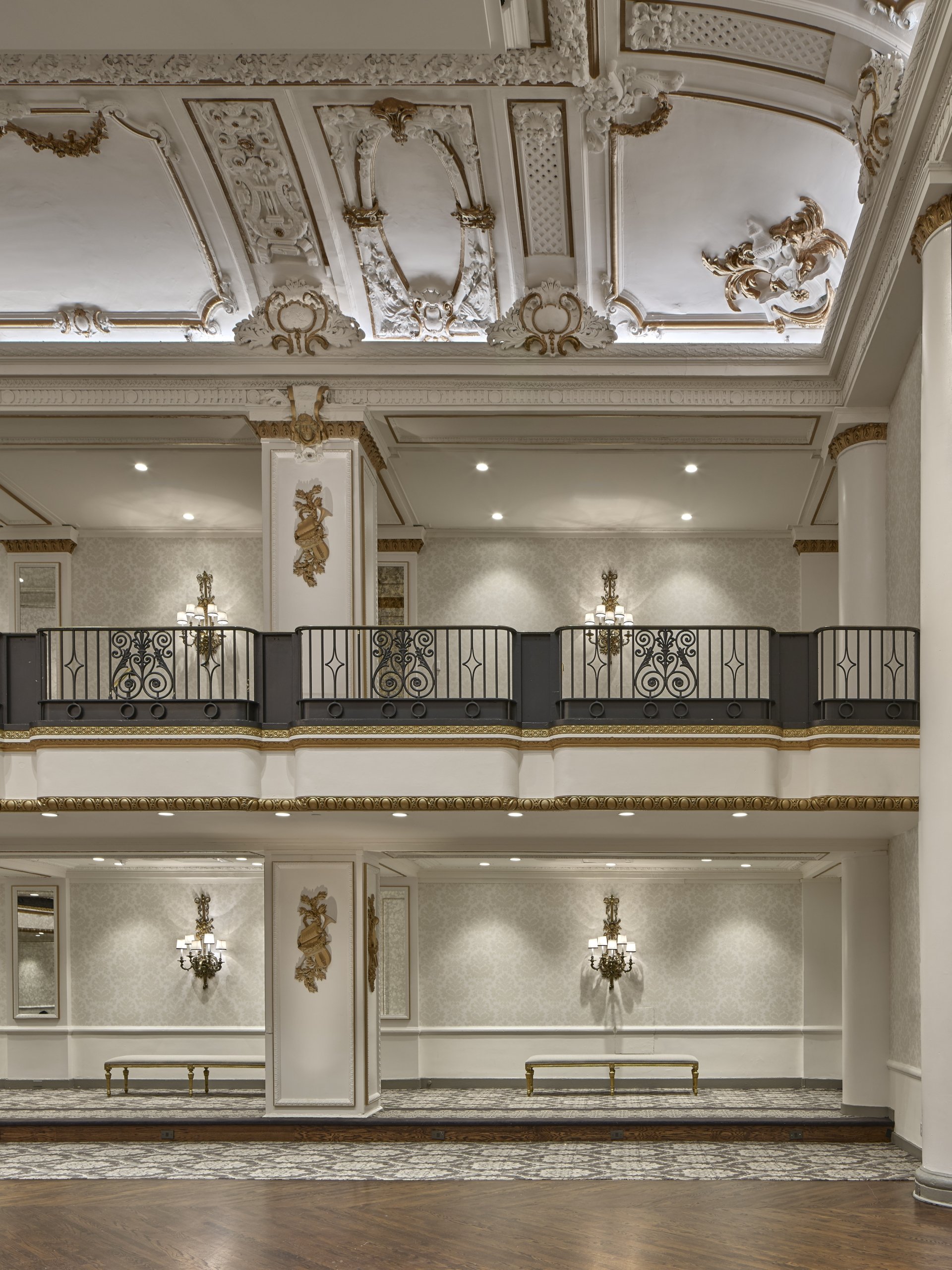 vaulted white ceiling with matte gold gilding over a mezzanine.